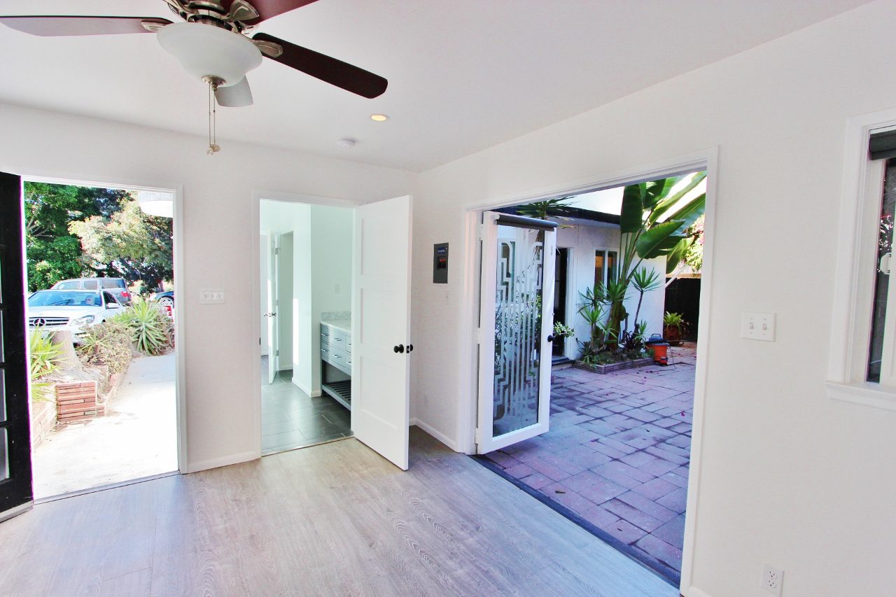 A room with a ceiling fan and sliding glass doors.