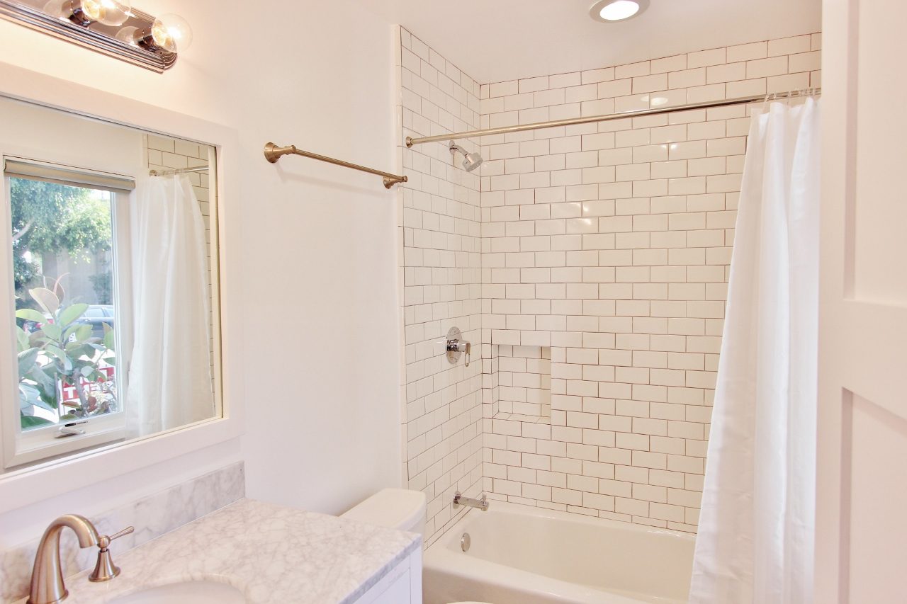 A bathroom with white tile and a tub / shower combination.