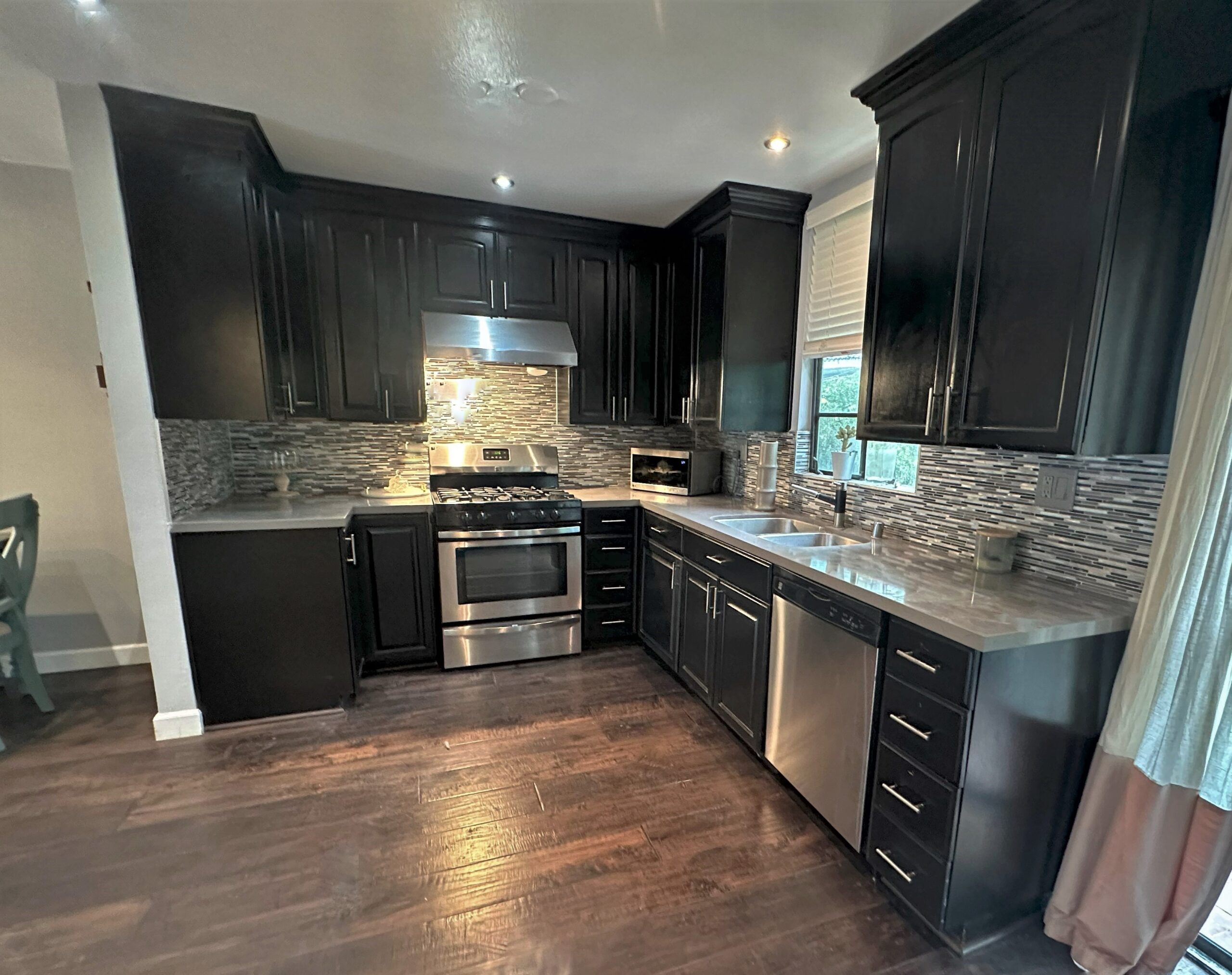 A kitchen with dark cabinets and wood floors.