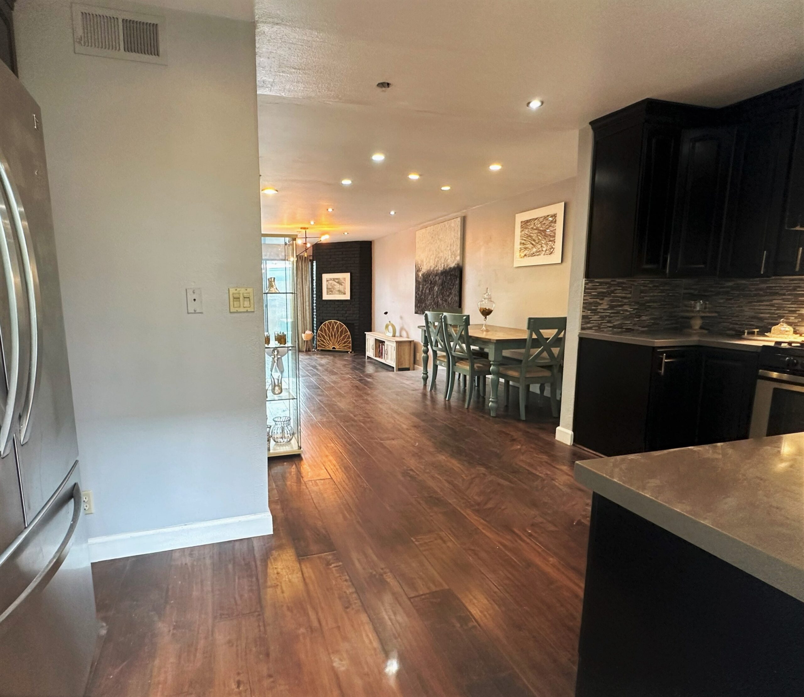 A kitchen with wooden floors and black cabinets.