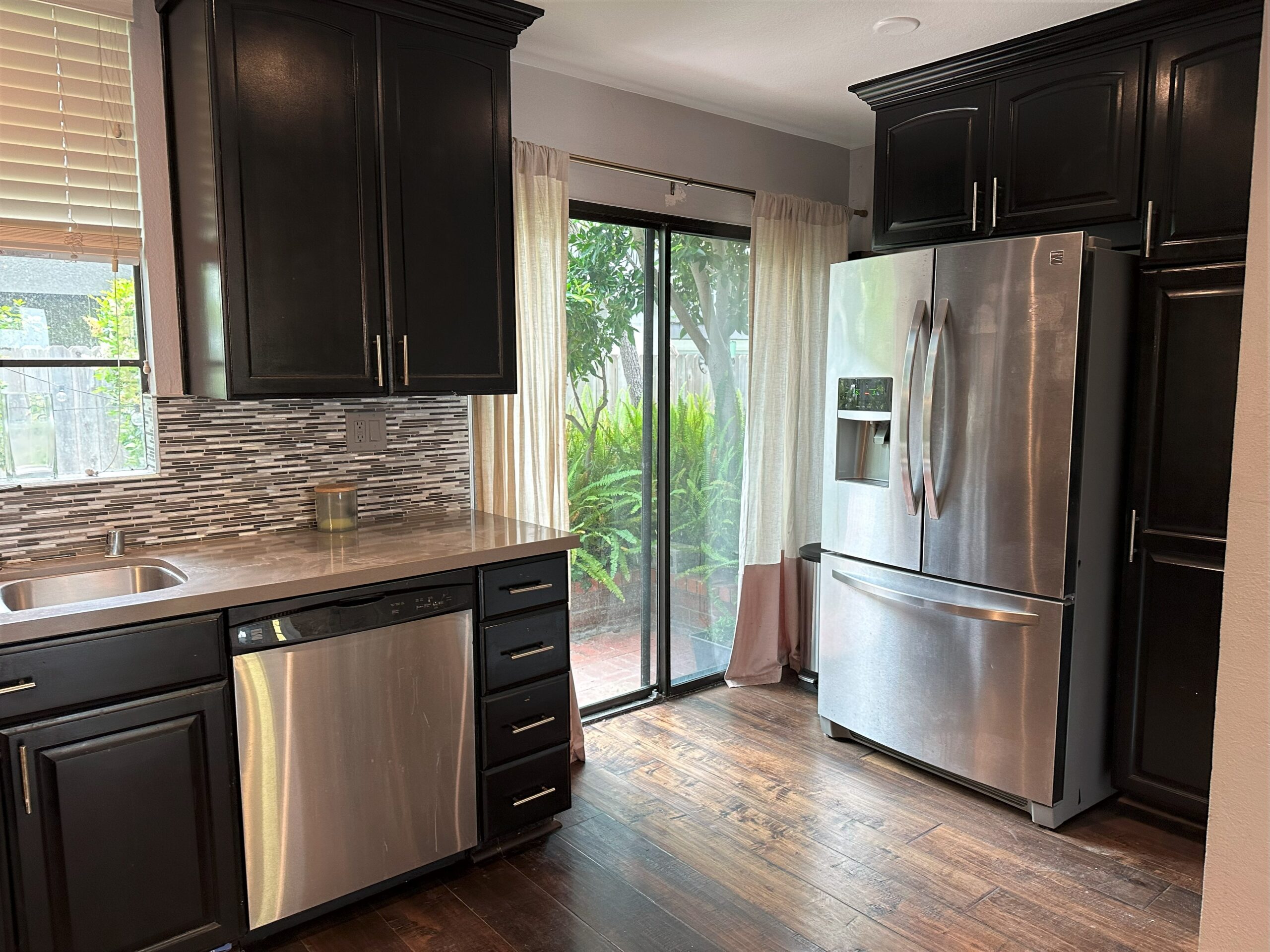 A kitchen with black cabinets and stainless steel appliances.