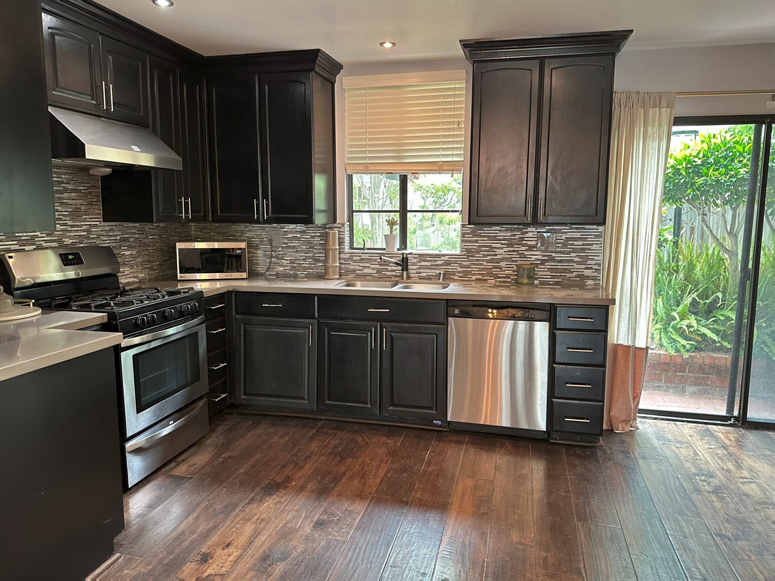 A kitchen with dark cabinets and wood floors.