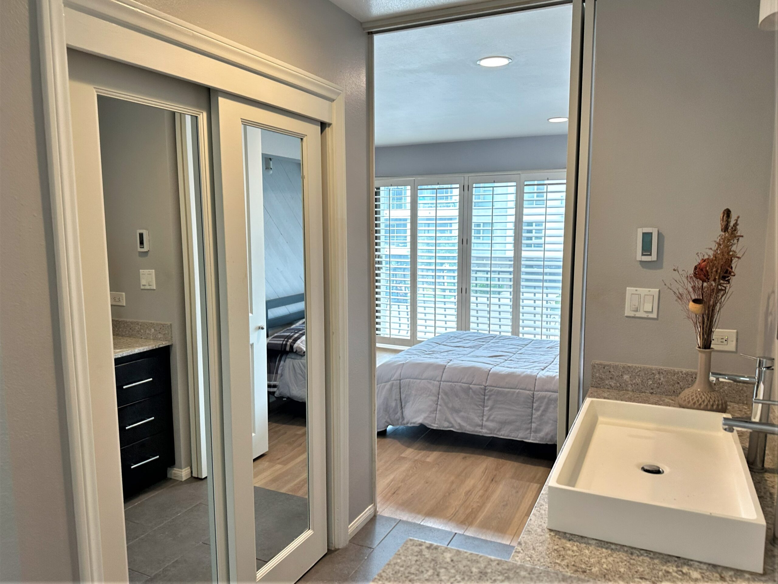 A bathroom with a sink, mirror and bed in it.