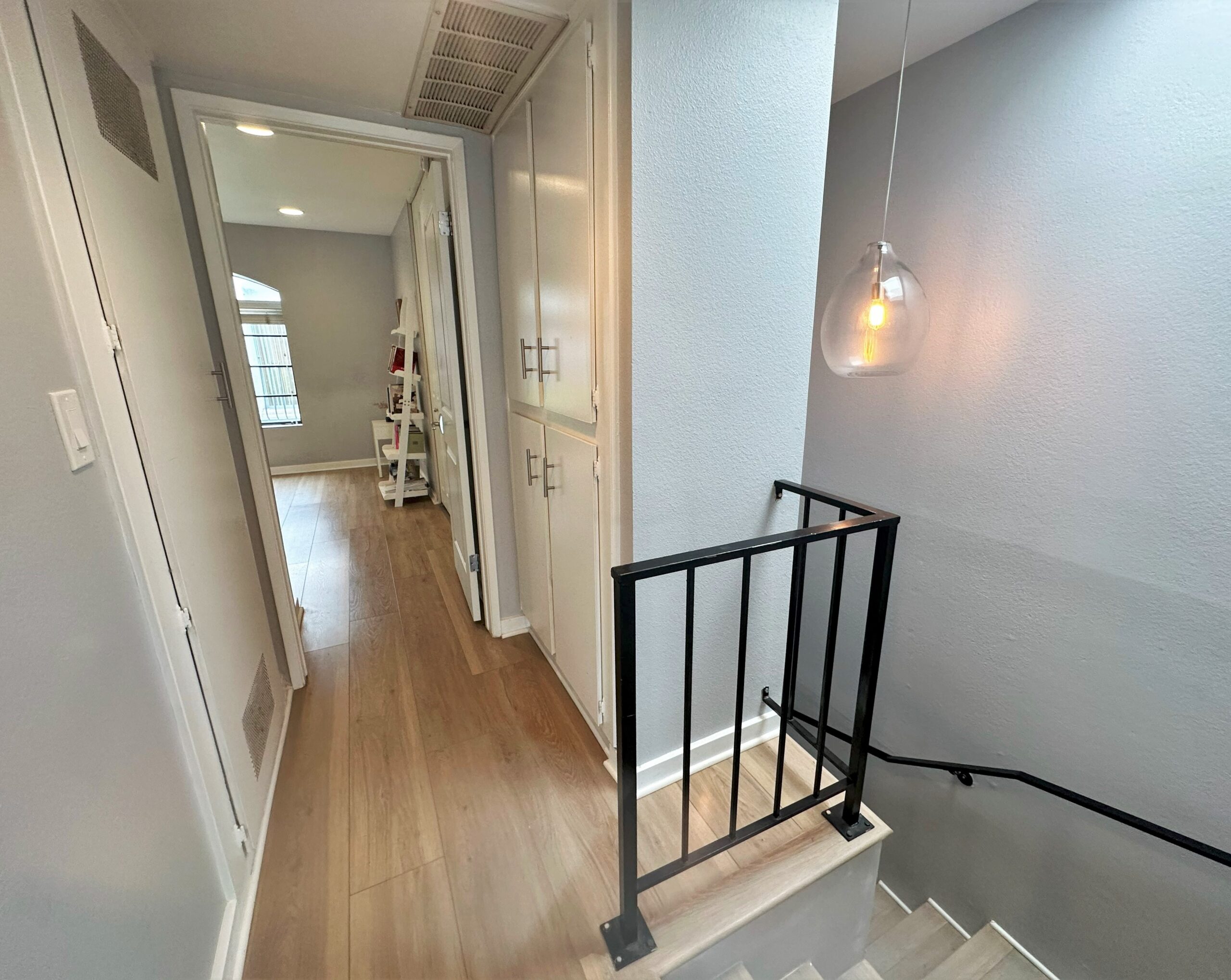 A hallway with stairs and a light hanging from the ceiling.