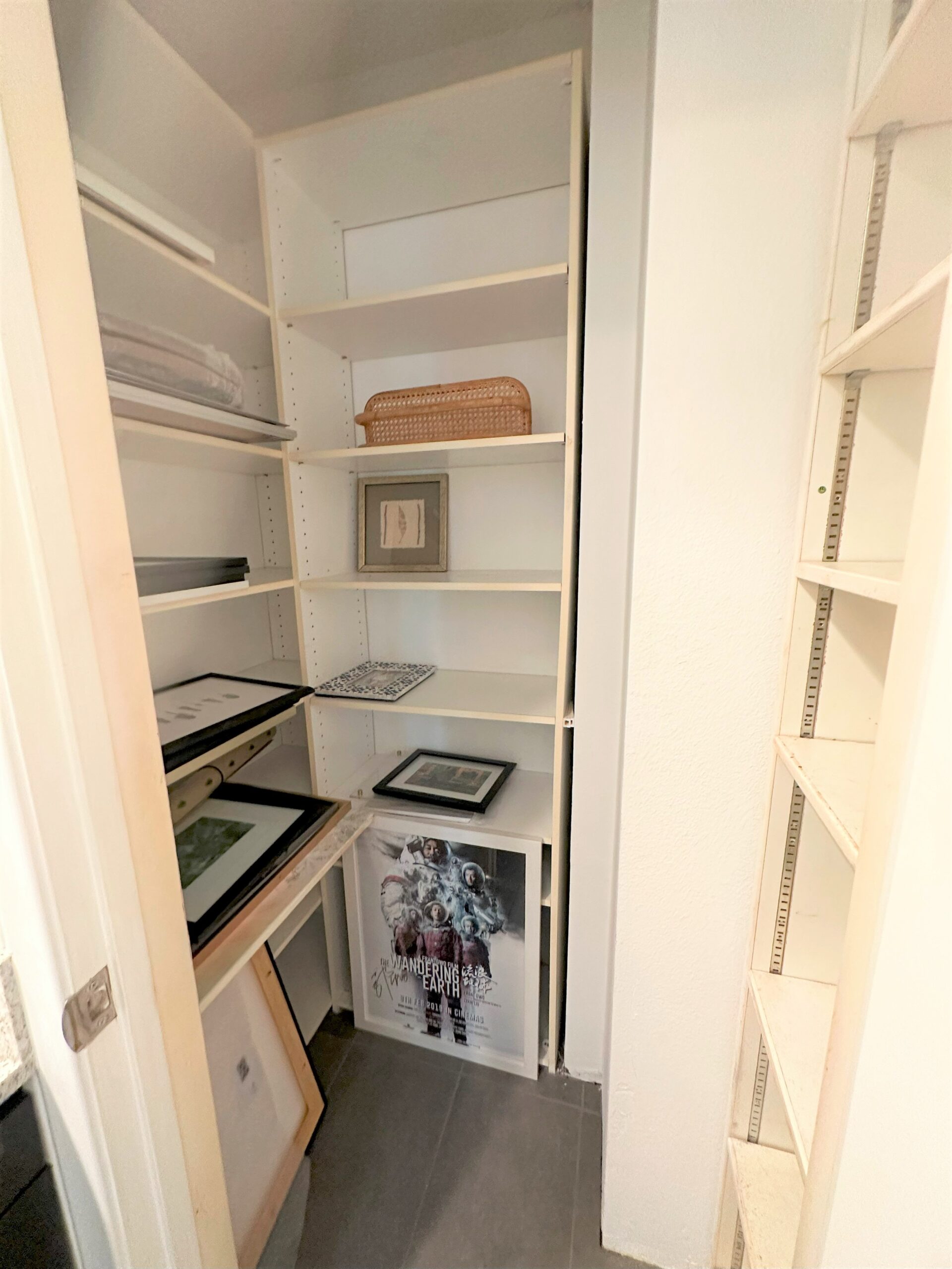 A white closet with many shelves and a desk.