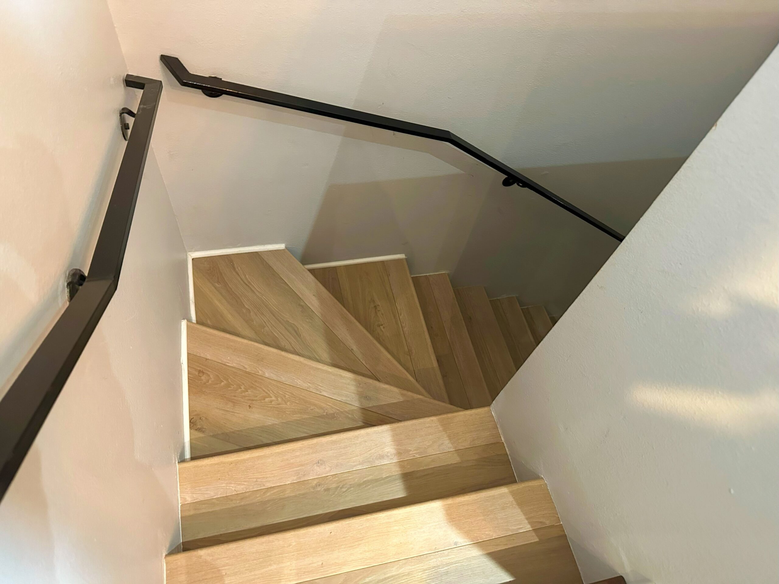 A wooden staircase with metal handrail and steps.