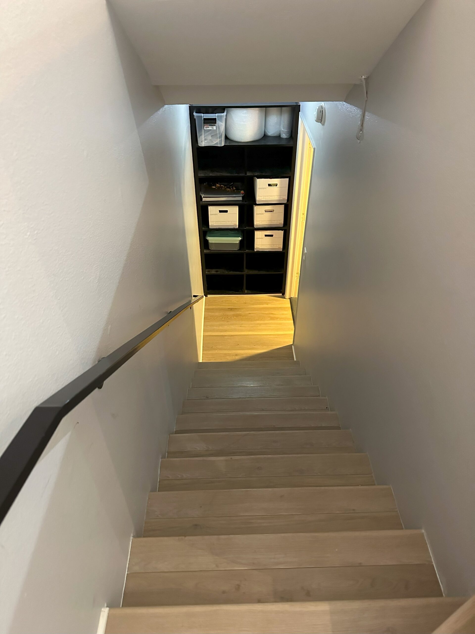 A staircase with a wooden handrail and a yellow door.