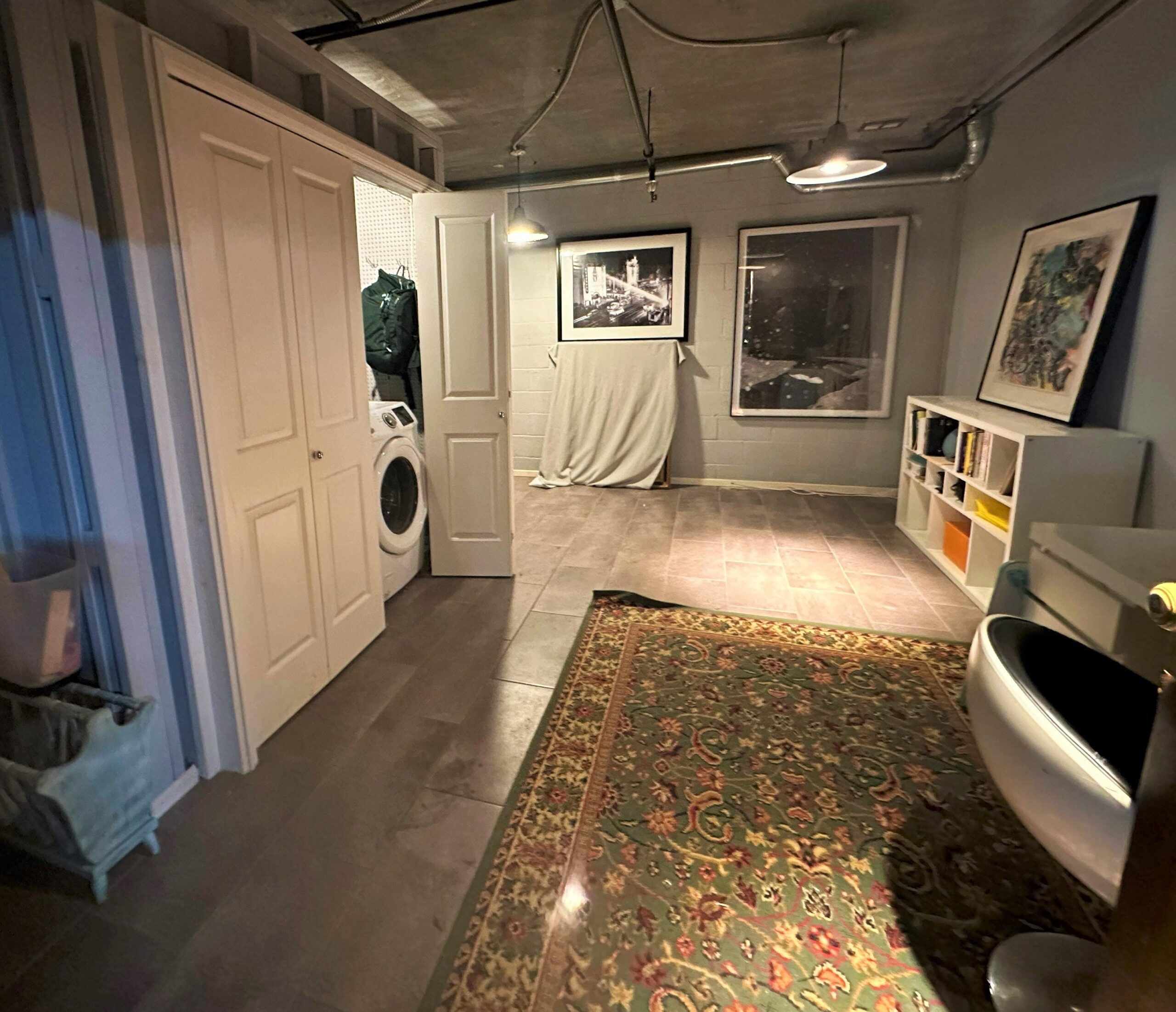 A room with a large rug and a washer in it