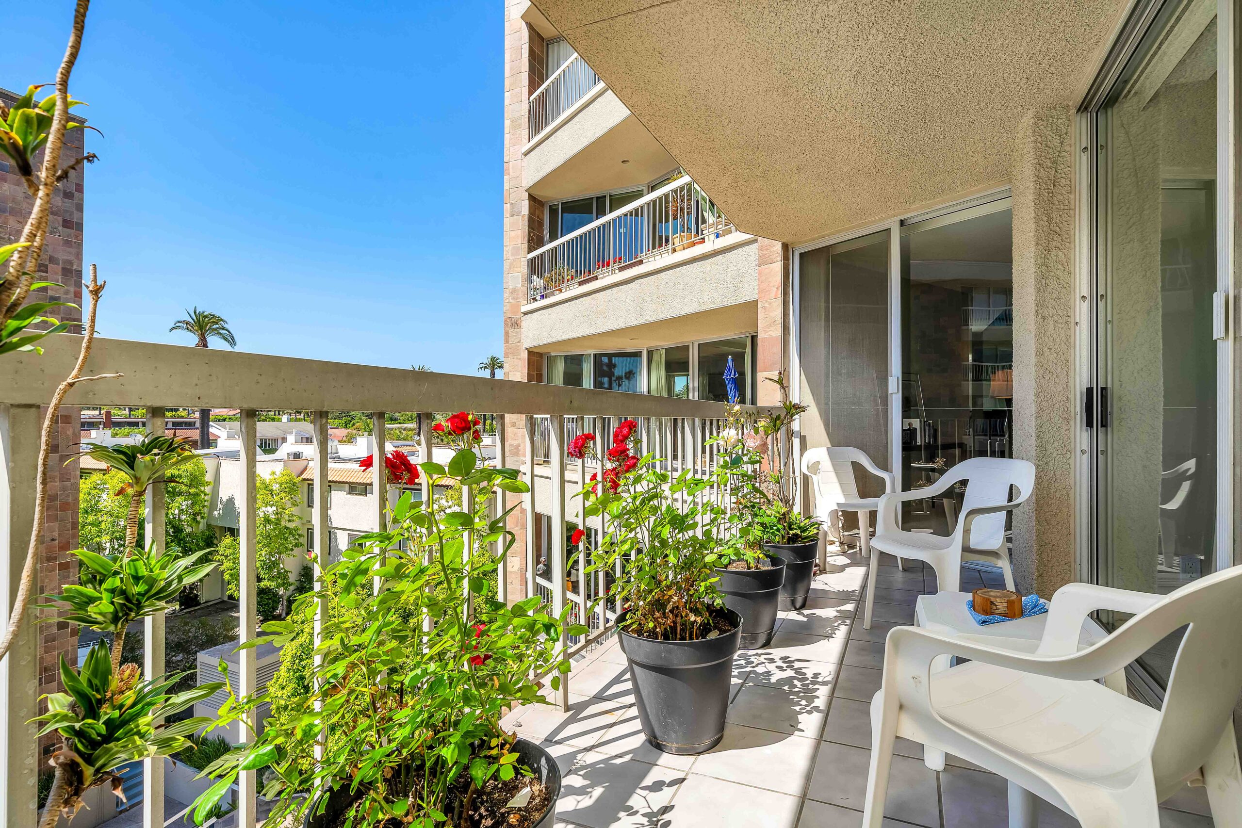 A balcony with chairs and potted plants on it.