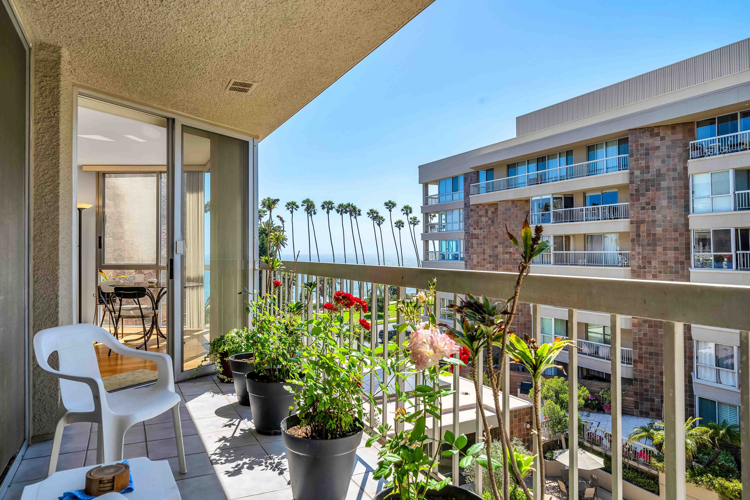 A balcony with potted plants and a view of the ocean.