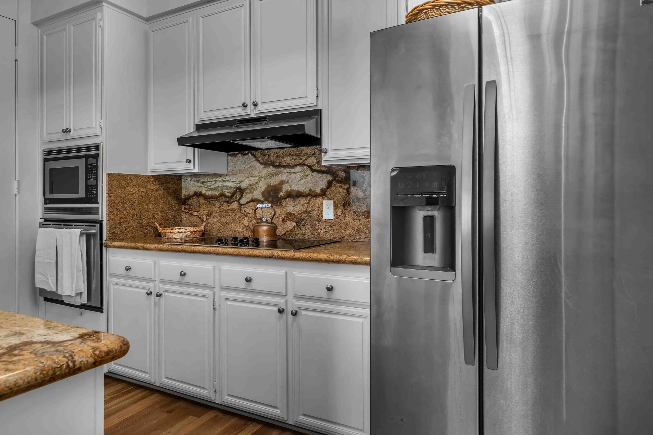 A kitchen with white cabinets and brown counter tops.