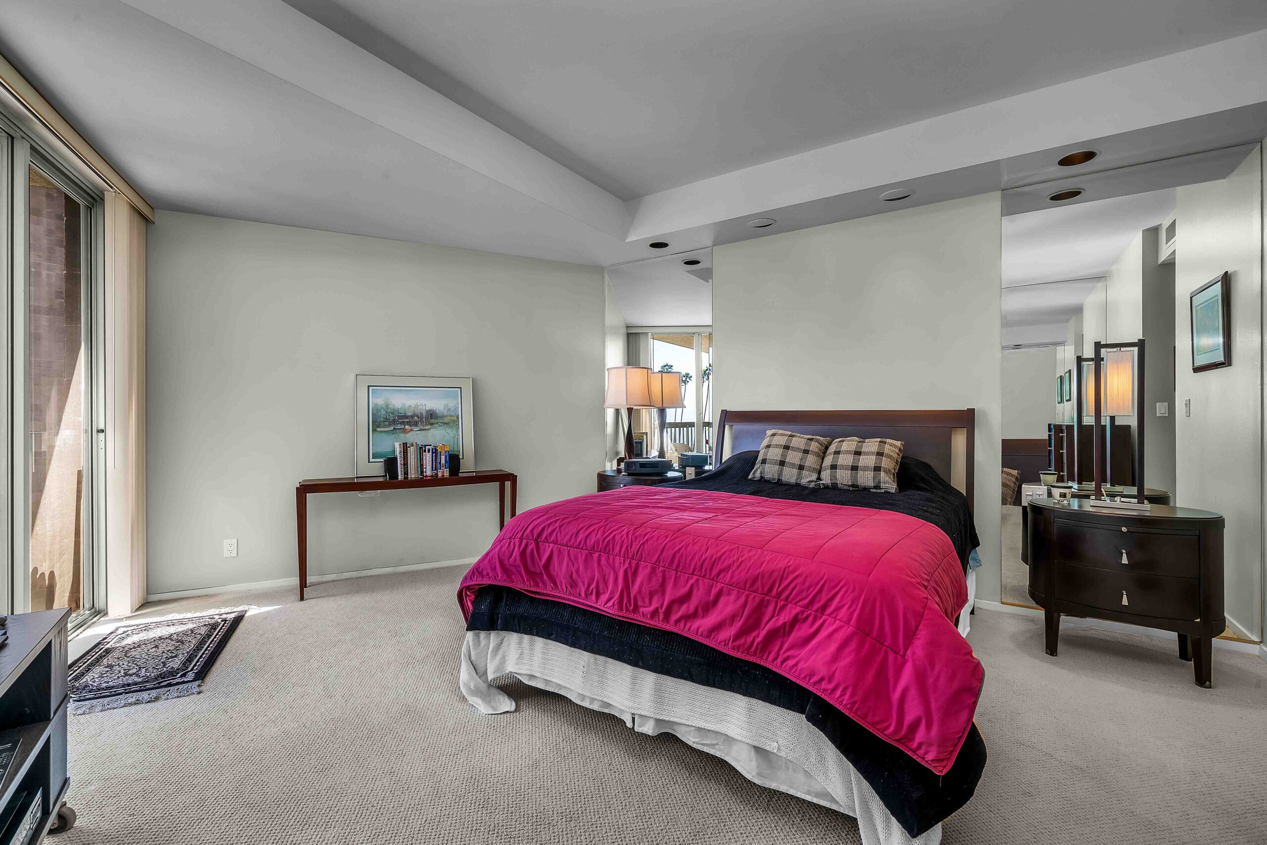 A bedroom with a bed, dresser and mirror.