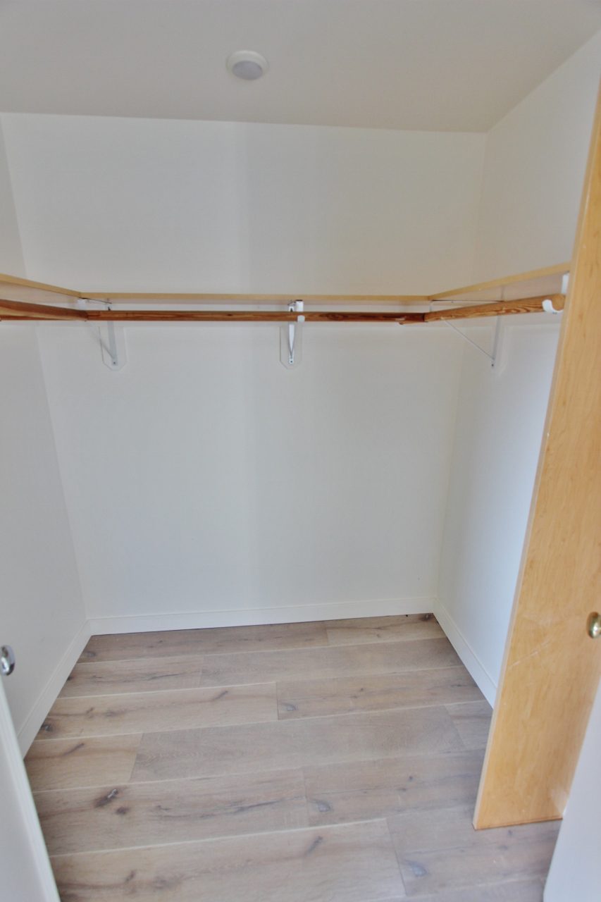 A closet with two hangers and a wooden floor.