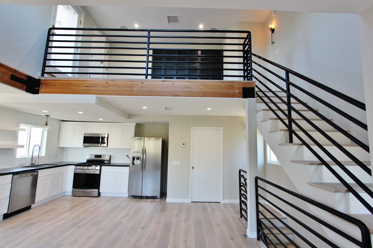 A kitchen with a stove, refrigerator and stairs.