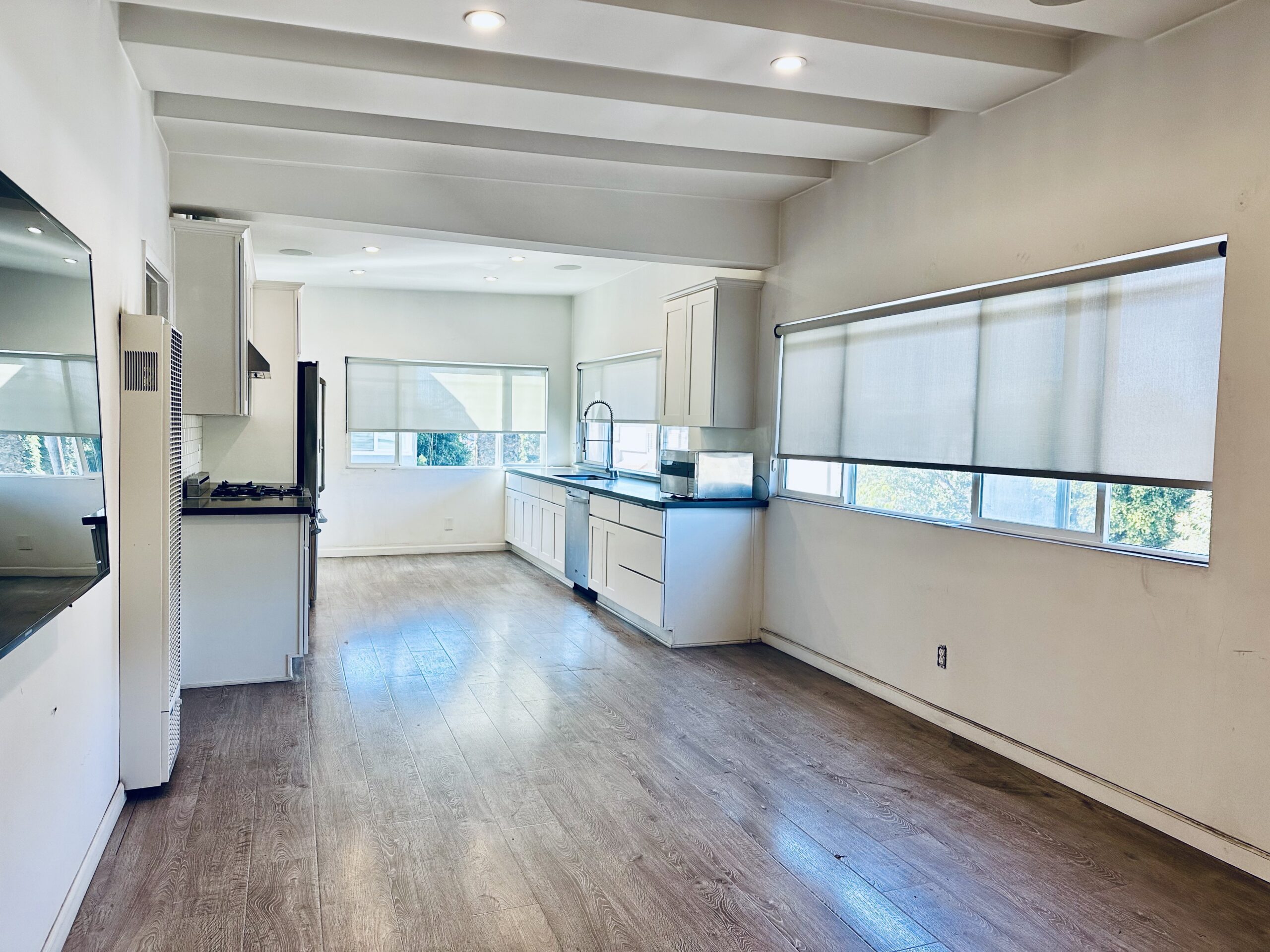 A kitchen with white walls and wooden floors.