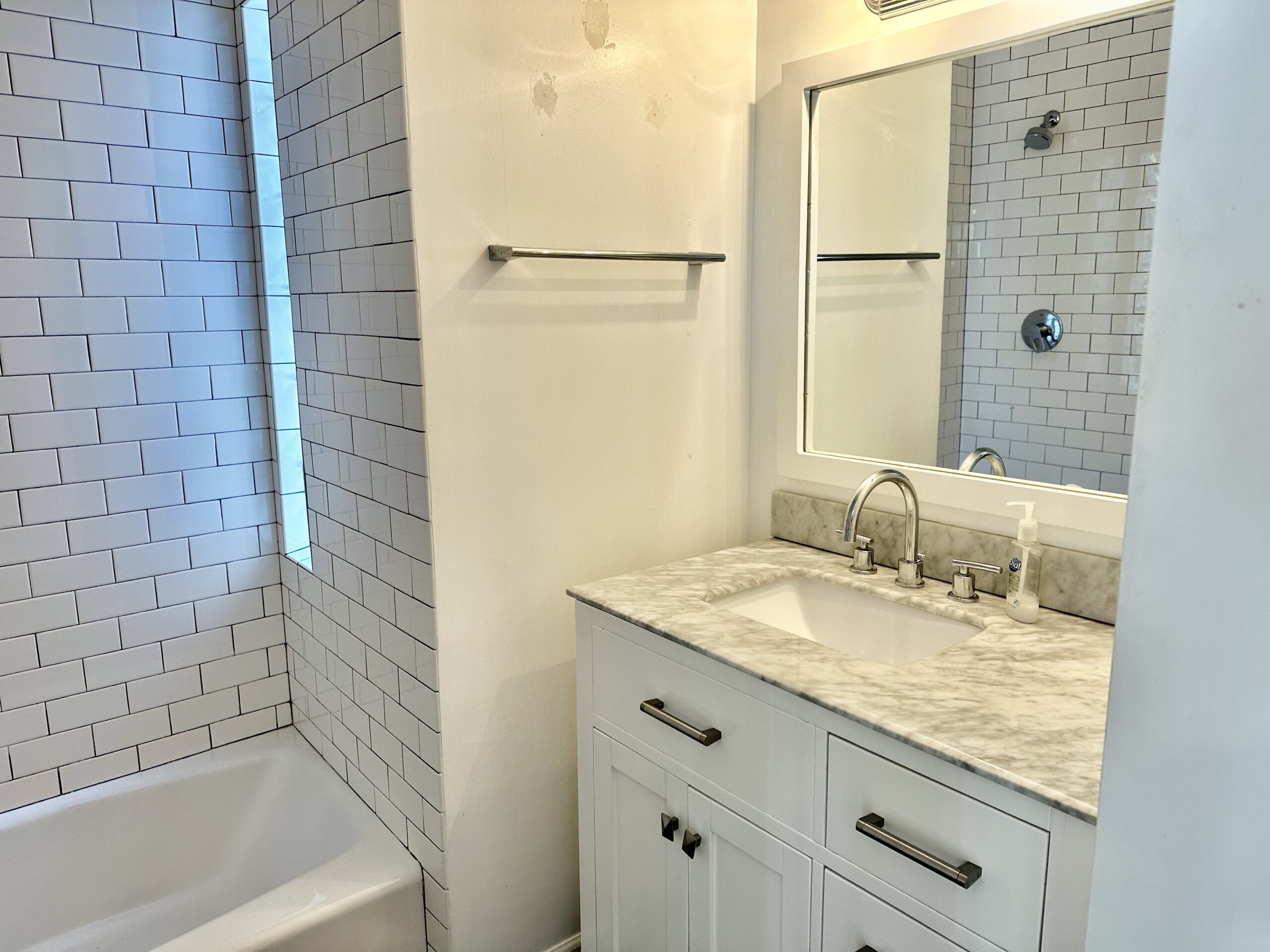 A bathroom with white walls and marble counter tops.