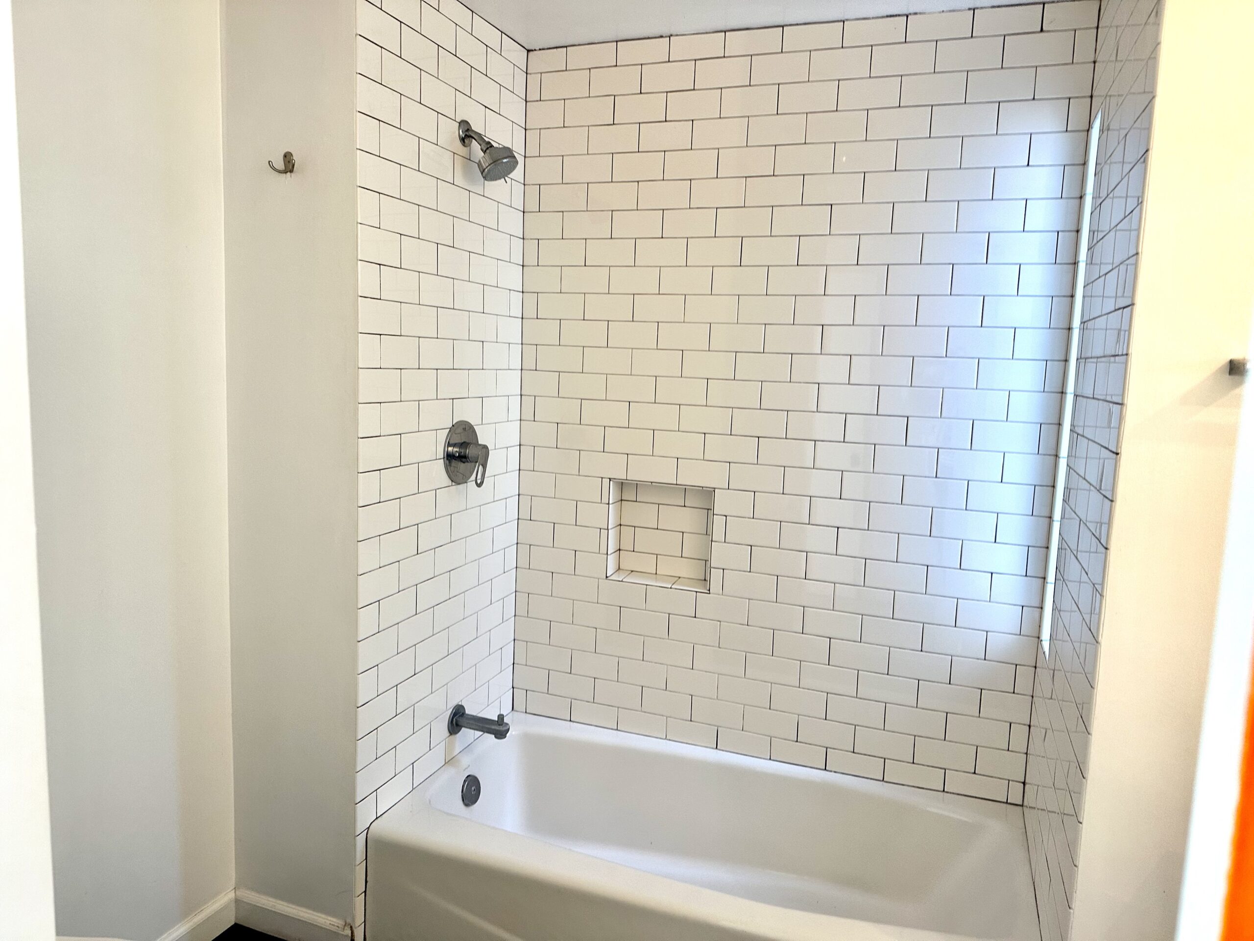 A bathroom with white tile and a tub.