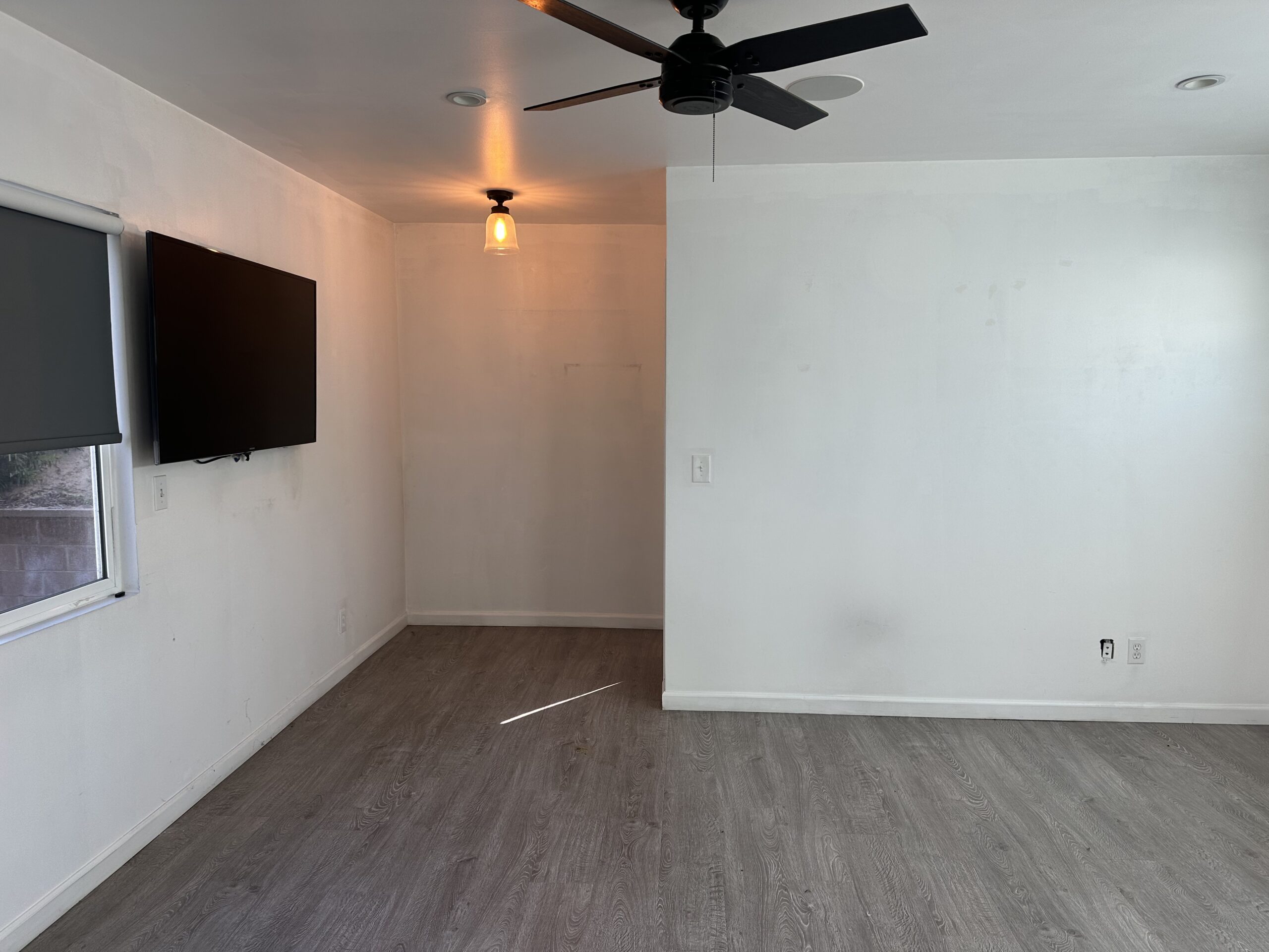 A room with a tv and ceiling fan in it