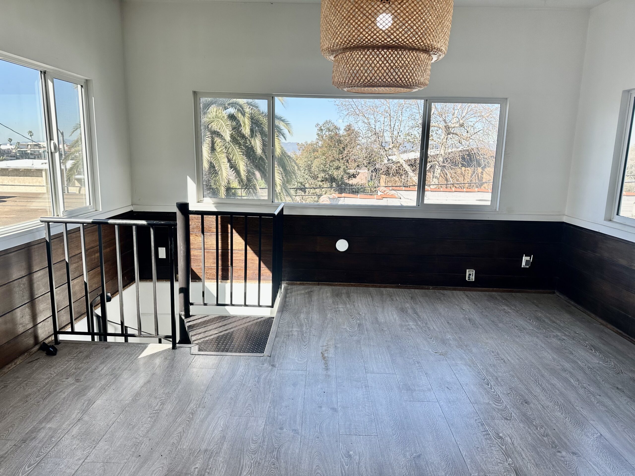 A room with a black and white wall, wooden floors and a large window.