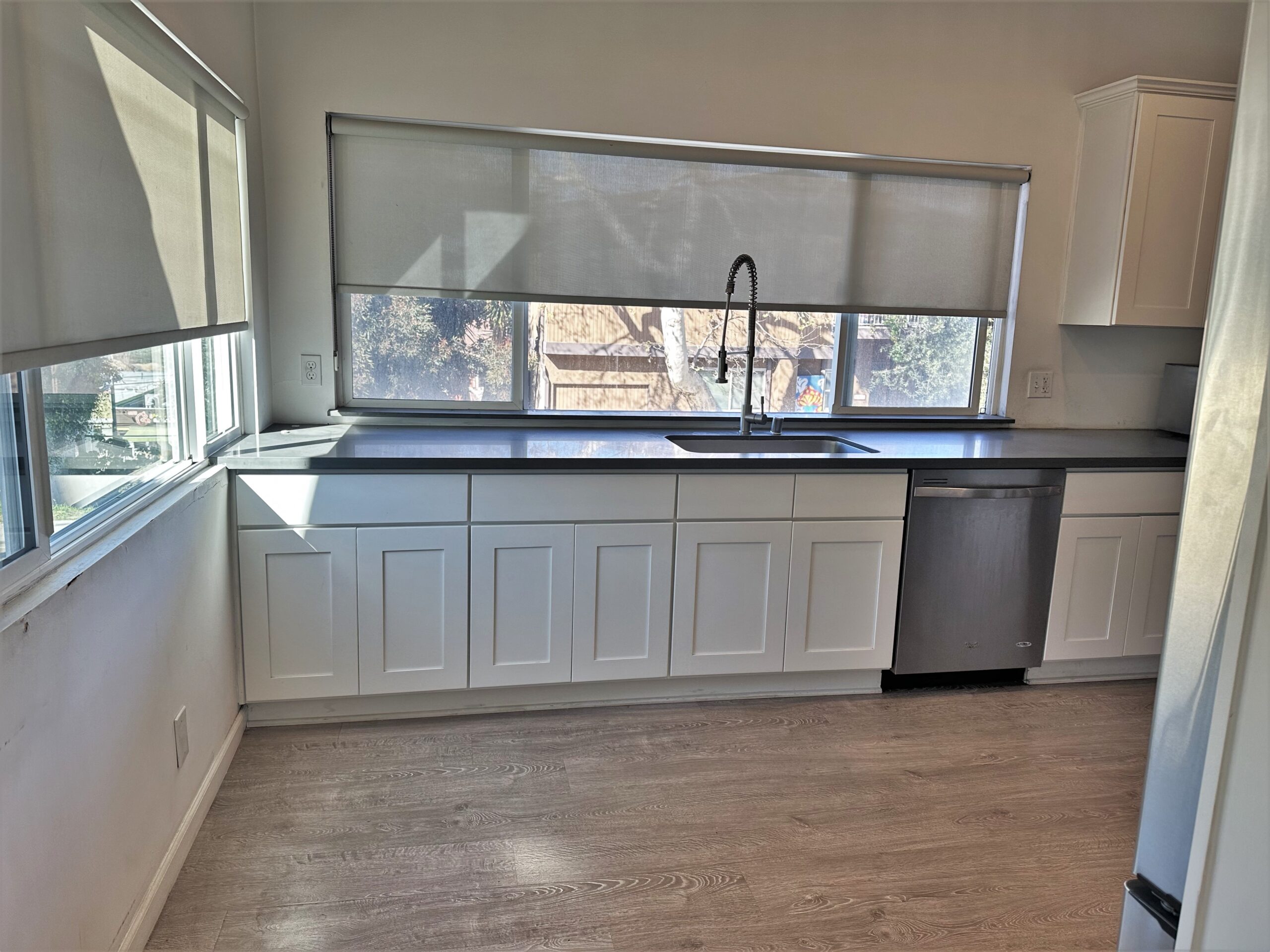 A kitchen with white cabinets and black counter tops.