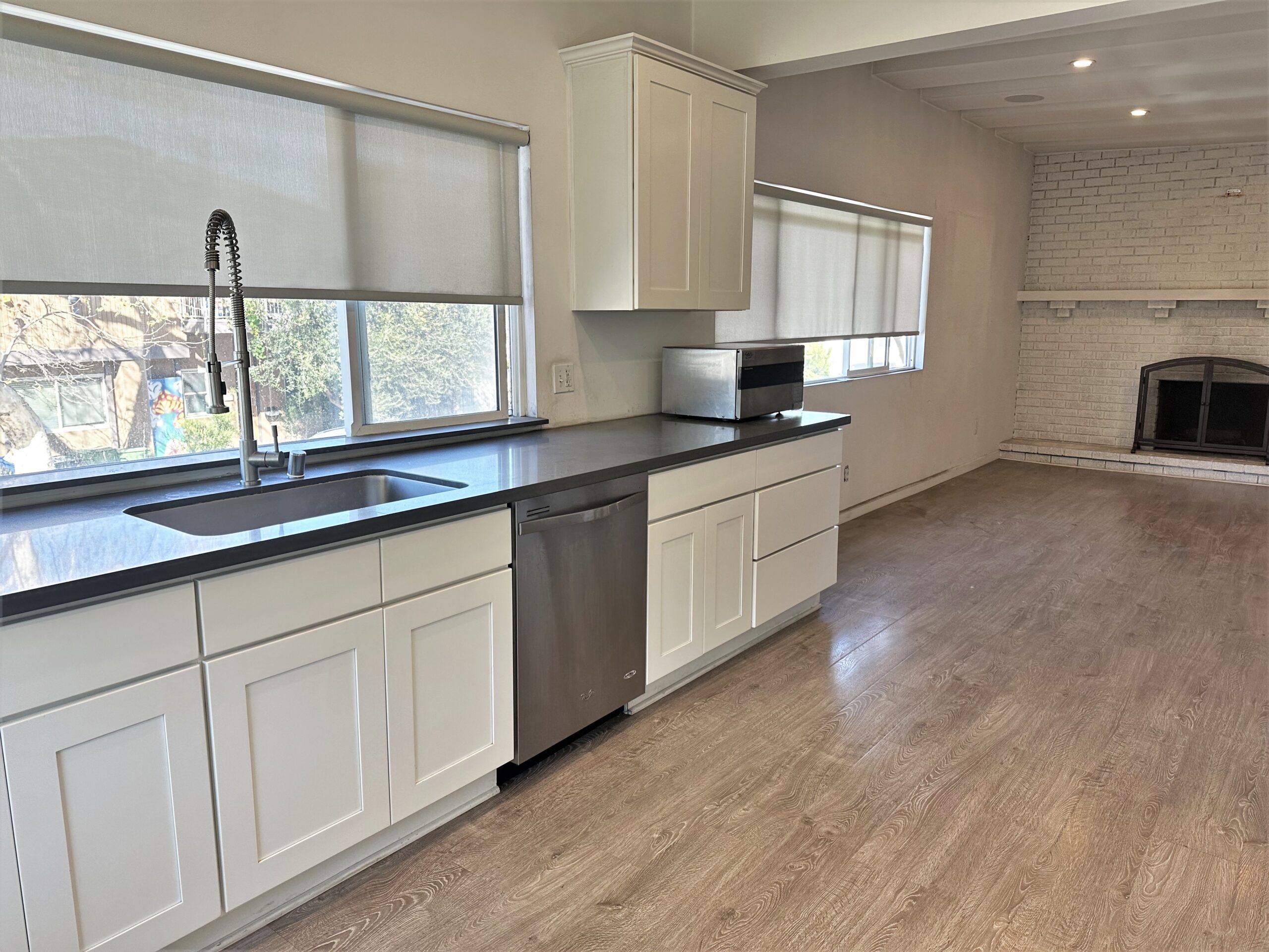 A kitchen with white cabinets and black counter tops.