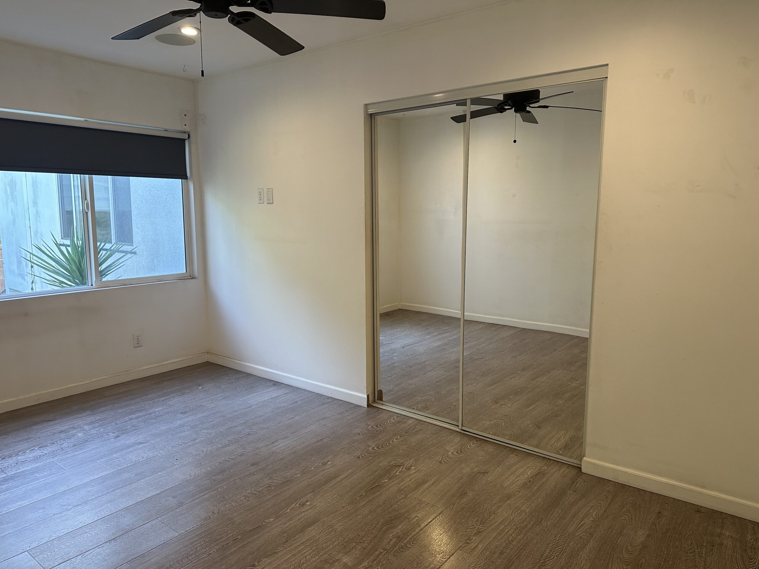 A room with a mirror and ceiling fan.