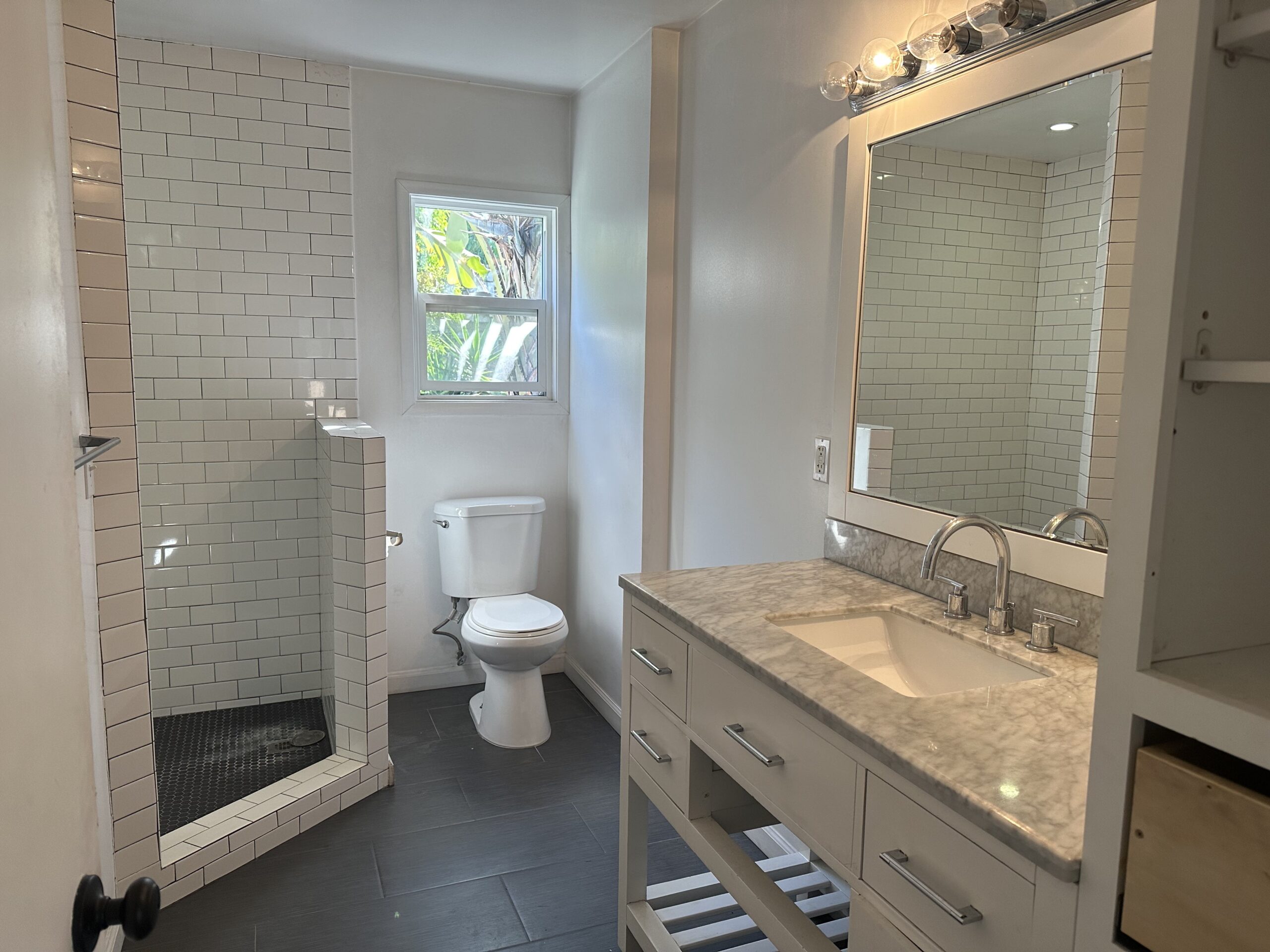 A bathroom with white tile and marble counter tops.