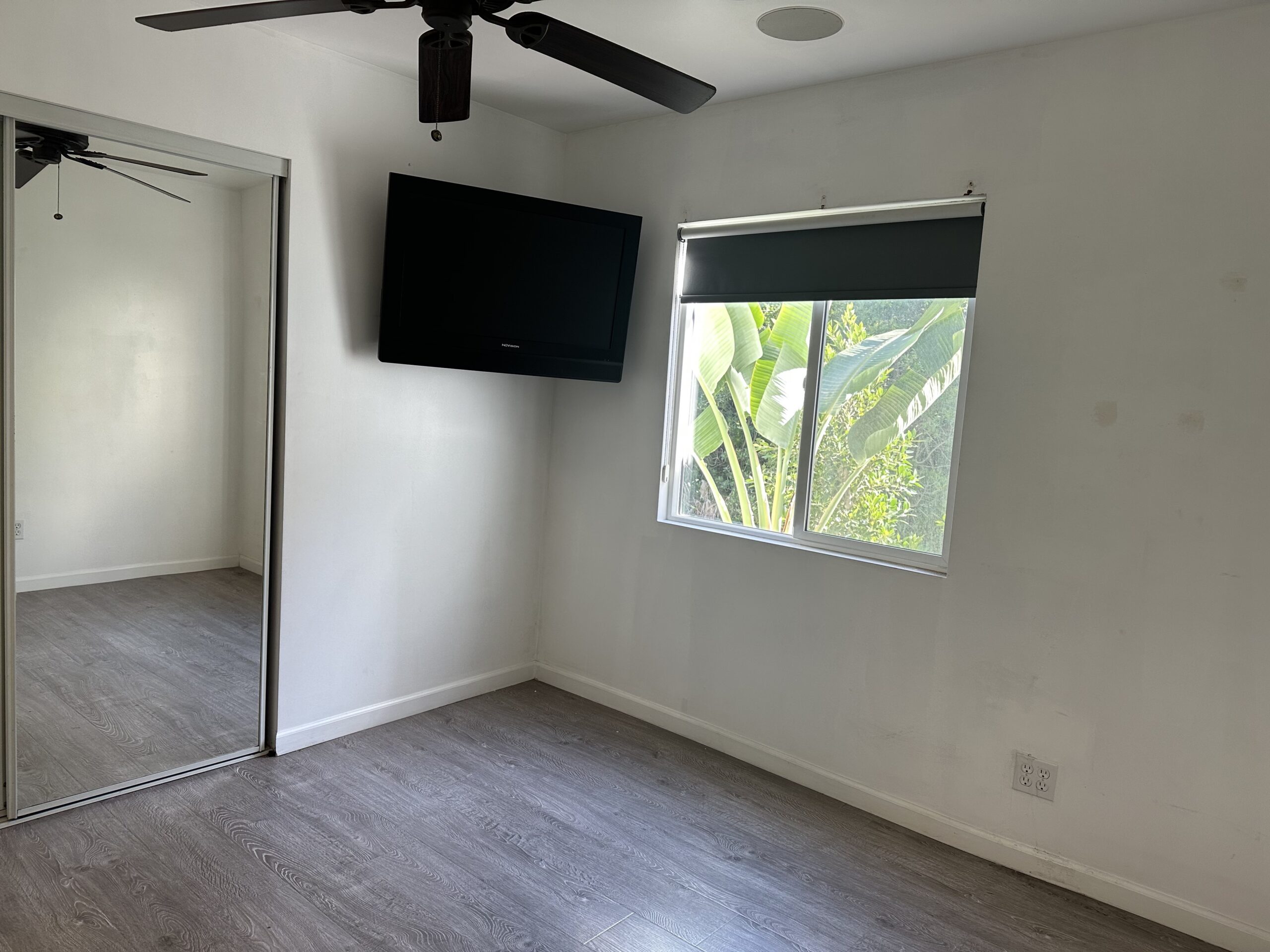 A room with a tv and a ceiling fan.