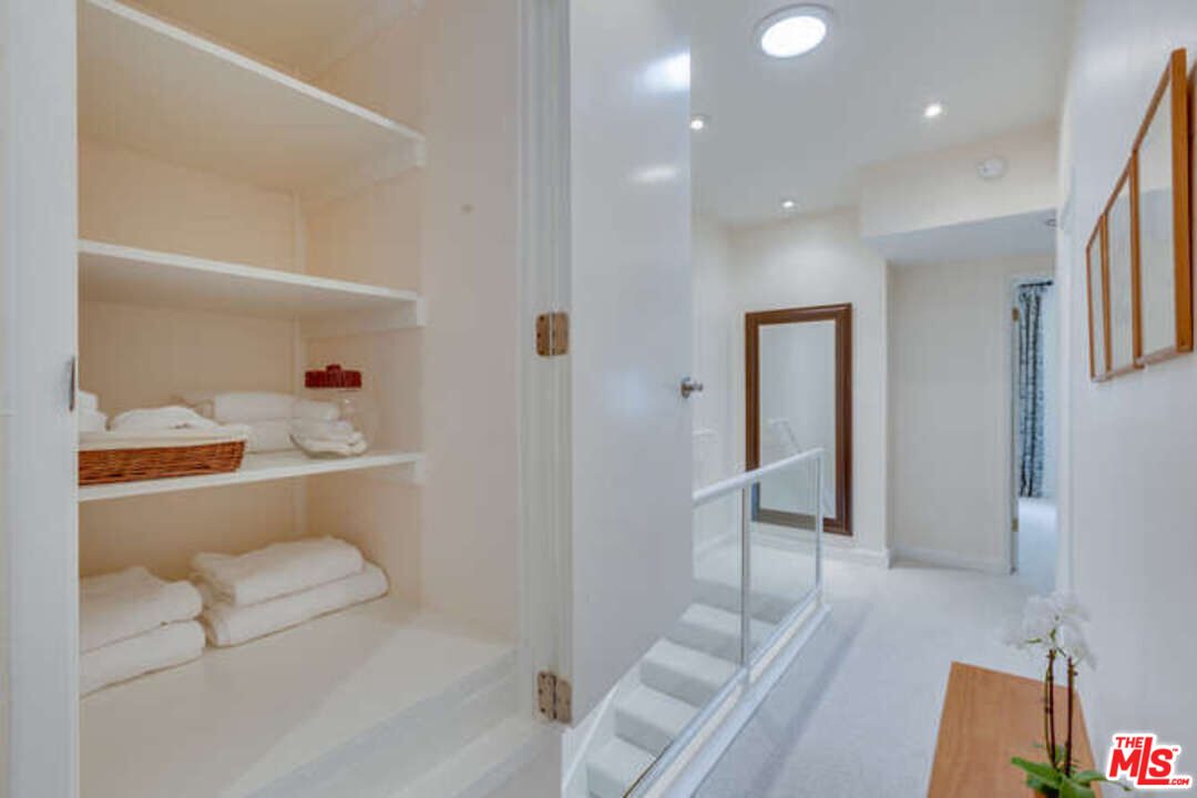 A bathroom with white walls and stairs leading to the shower.
