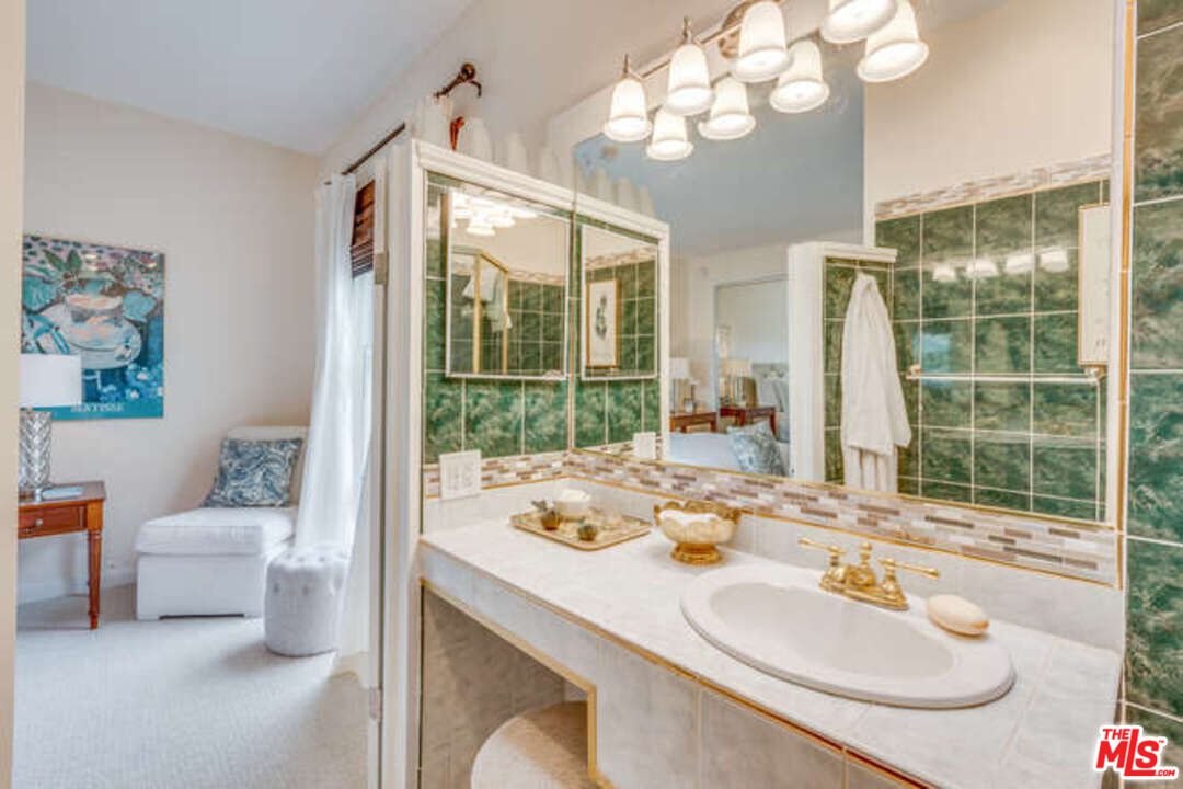 A bathroom with green tiles and white counter tops.
