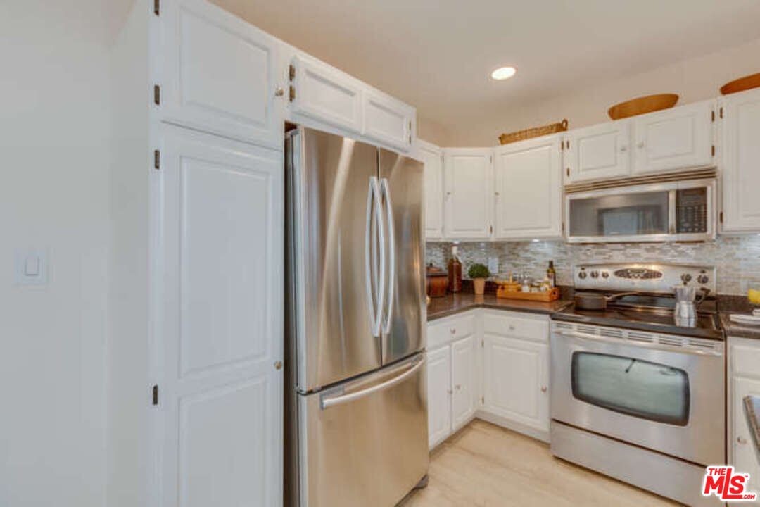A kitchen with white cabinets and stainless steel appliances.
